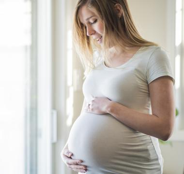 Bilden visar en gravid kvinna vid ett fönster